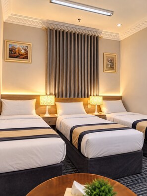 A hotel room with three beds, a large window with curtains, and two wall-mounted lamps. - Sakab Al Aseel Hotel  (Makkah)