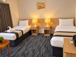 A hotel room with two beds, a small table, a chair, a potted plant, and a painting on the wall. - Sakab Al Aseel Hotel  (Makkah)