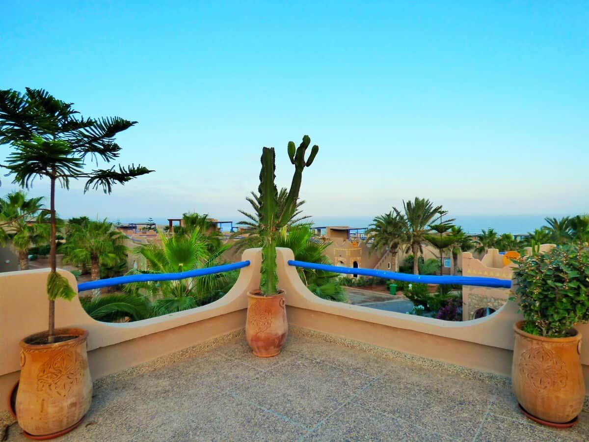Une terrasse sur le toit, agrémentée de plantes en pot, dotée d’une rambarde et offrant une vue sur la côte.