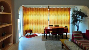 Uma área de refeições com mesa, cadeiras, um sofá e uma planta.