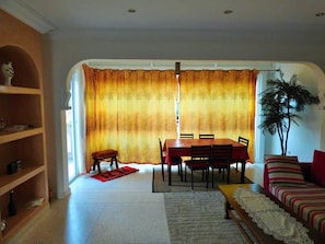 A dining area with a table and chairs, a sofa, and a plant. - Villa Club Evasion, Right on the Atlantic and Pool Access (Mirleft)