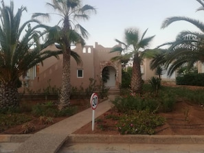 A building with a stone facade, palm trees, and a speed limit sign.