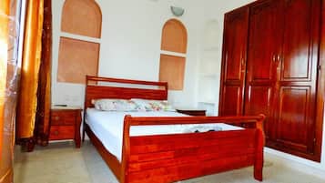Un dormitorio con una cama de madera, una mesita de noche, un armario y aire acondicionado instalado en la pared.