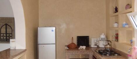 A compact kitchen with a refrigerator, a stove, and a sink.