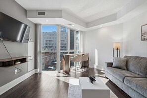 Ein modernes Wohnzimmer mit einem grauen Sofa, einem Couchtisch und einem an der Wand montierten Fernseher.