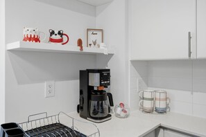 A kitchen with a coffee maker, a shelf with decorative items, and a glass rack with mugs. - Modern 1BR - Walk to CN Tower - Sleeps 4 (Toronto)