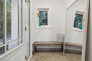 A room with a bench, a small window, and a mirror reflecting the window.