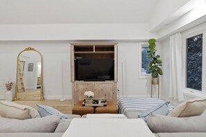A living room with a television, sofa, and a large mirror.