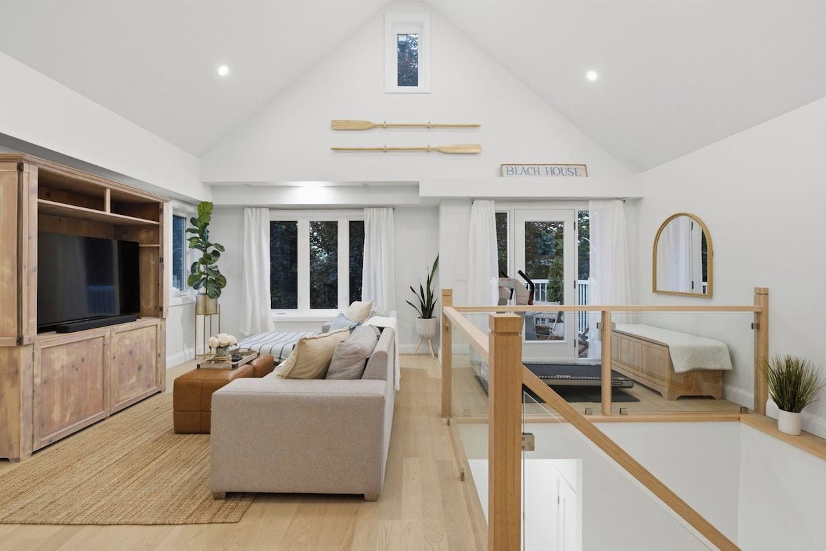 A modern living room with a large flat-screen TV, a sofa, and a wooden entertainment unit.