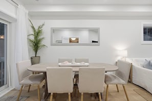 A dining area with a round table, four chairs, a potted plant, and a mirror on the wall.