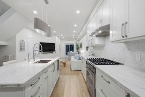 A modern kitchen with white cabinetry, a built-in stove, and a large island with a sink.