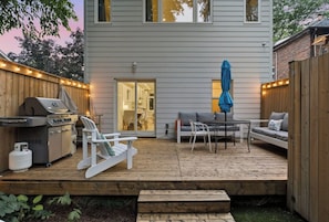 A deck with a grill, seating, and a covered table.