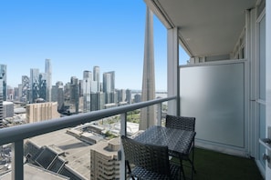 Ein Balkon mit Blick auf eine Stadtlandschaft, einem Tisch und zwei Stühlen.