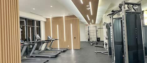 A gym with treadmills, weight machines, and a mirrored wall.