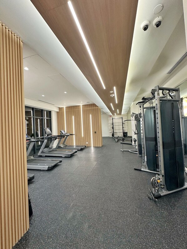 Ein Fitnessstudio mit Laufbändern, Kraftgeräten und einer Spiegelwand.