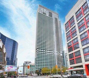 A tall, modern building with a grid-like facade, surrounded by other buildings and a busy street. - Amazing CN Tower View 2BR Condo - Downtown Toronto (Toronto)