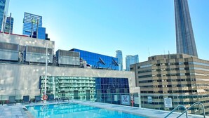 Una piscina en la azotea con vistas a un horizonte urbano, que incluye una torre alta y edificios modernos.