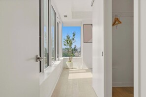 A corridor with a potted plant, a view of the city, and a door with a hanger. - 2BR Yorkville Retreat - Balcony & Views (Toronto)