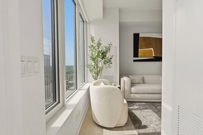 A modern living room with a large window, a white sofa, and a decorative plant. - 2BR Yorkville Retreat - Balcony & Views (Toronto)