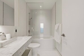 Un baño moderno con cabina de ducha de vidrio, inodoro blanco y lavabo de mármol.