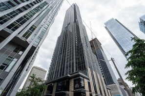 Un rascacielos alto y moderno con fachada de vidrio y un llamativo elemento vertical.