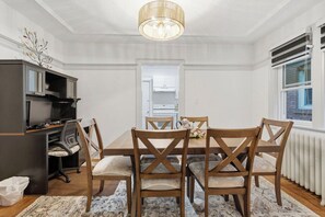 A dining area with a table set for four, surrounded by wooden chairs with cushioned seats.