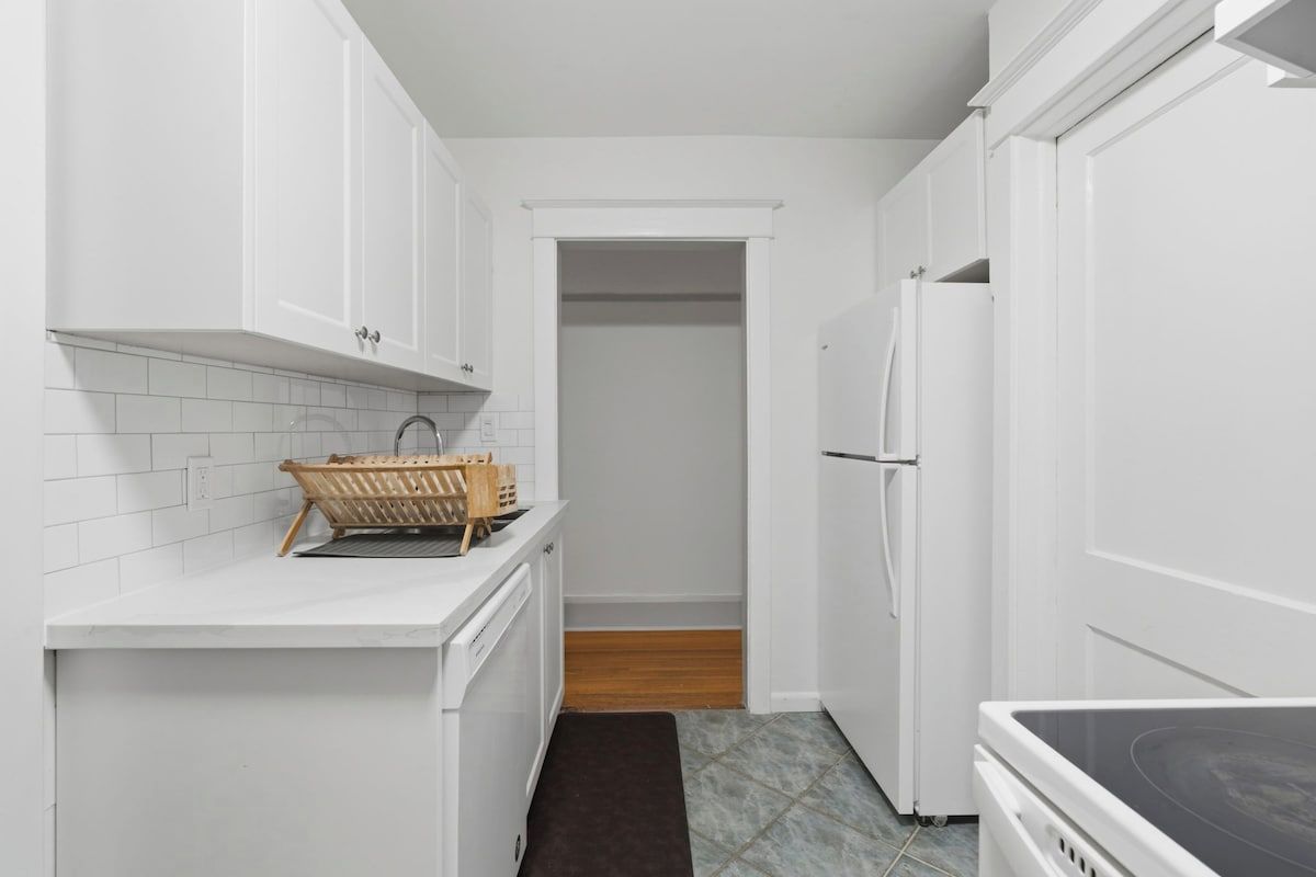 A kitchen with white cabinets, a built-in oven, and a refrigerator.