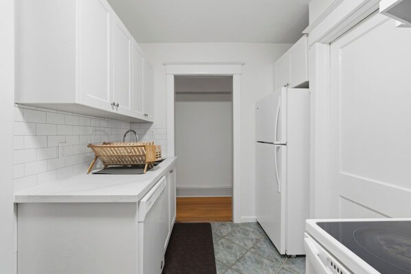 A kitchen with white cabinets, a built-in oven, and a refrigerator.