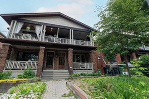 A two-story house with a front porch, a balcony on the upper floor, and a brick facade.