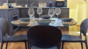 Un coin repas avec une table ronde dressée pour quatre personnes, entourée de chaises noires.