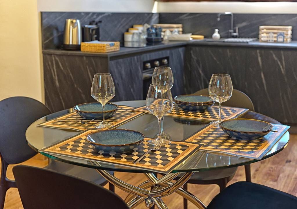 A dining table with four chairs, each with a glass top and a patterned placemat.