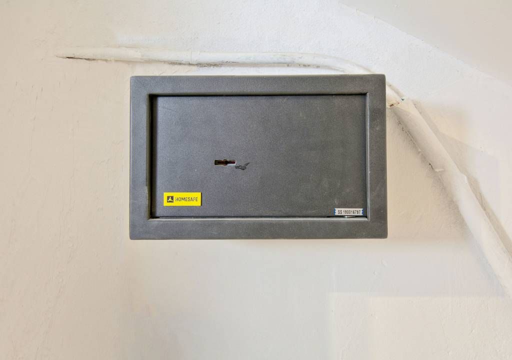 Caixa elèctrica fixada a la paret amb un forat visible, un adhesiu 'HOMESAFE' i una etiqueta amb un número de sèrie.
