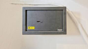 Caixa elèctrica fixada a la paret amb un forat visible, un adhesiu 'HOMESAFE' i una etiqueta amb un número de sèrie.