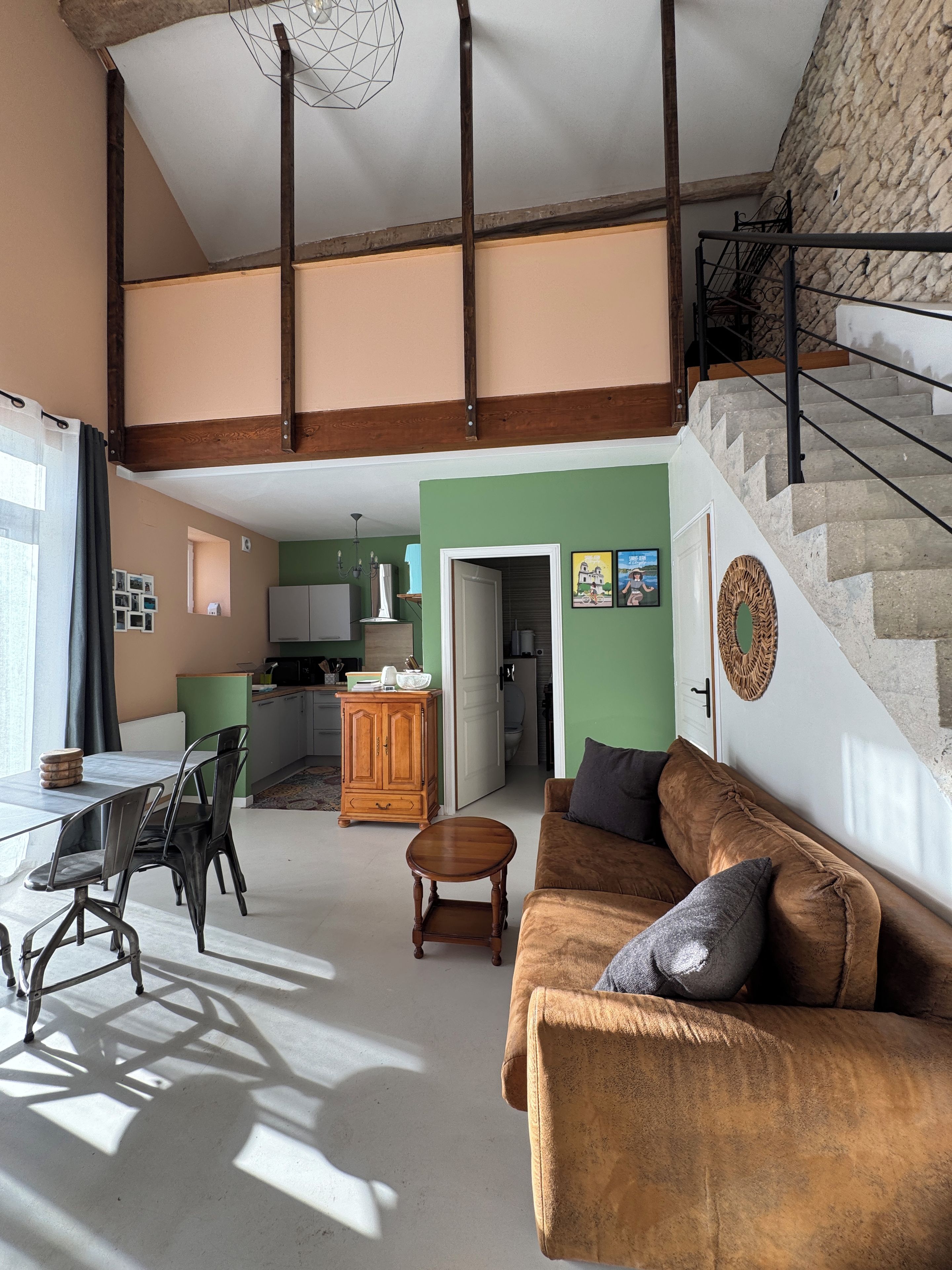 Un vaste espace de vie doté d’un haut plafond, d’un escalier et d’une cuisine située au fond de la pièce.