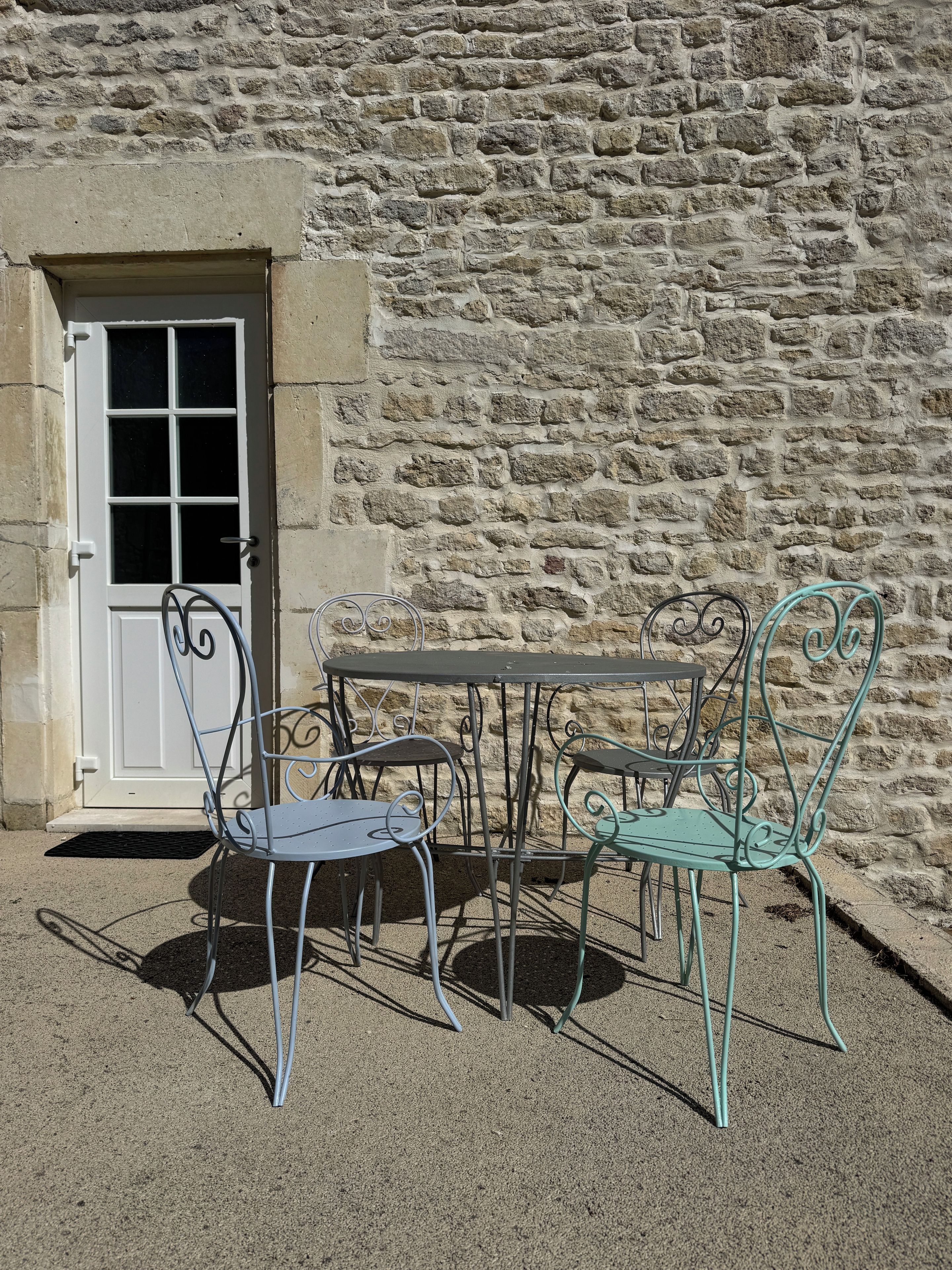 A stone wall with a metal table and chairs outside a building.