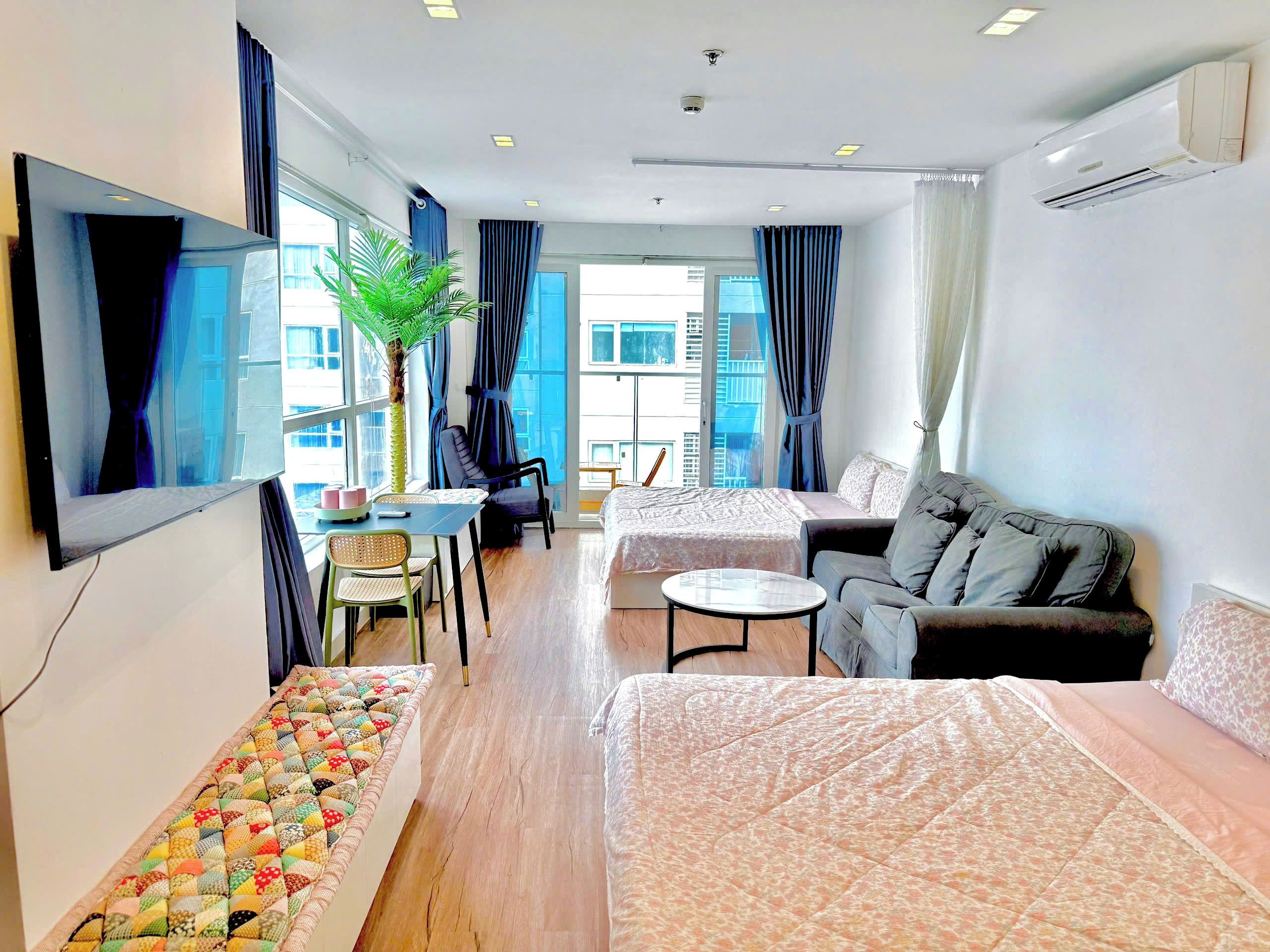 Een moderne hotelkamer met een bed, een sofa, een eettafel en een groot raam.