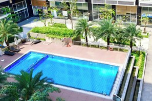 Une piscine sur le toit, agrémentée de chaises longues et de palmiers.