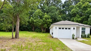 Een gelijkvloers huis met garage, omgeven door een gazon en bomen.