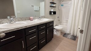 Een moderne badkamer met twee wasbakken, een toilet en een douche.