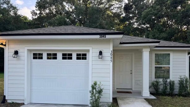 Een gelijkvloers huis met een witte garage en een voordeur.