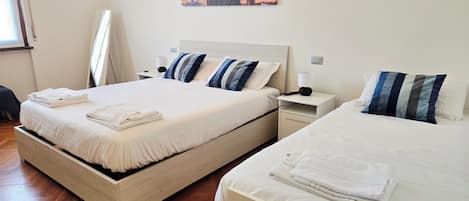 A hotel room with two beds, a nightstand, a lamp, and a painting on the wall.