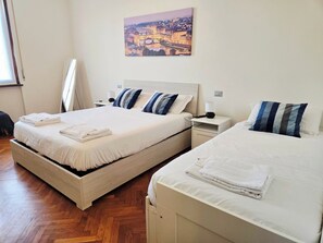 Camera d'albergo con due letti, un comodino, una lampada e un quadro appeso al muro.