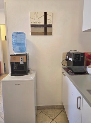 Eine Küchenzeile mit Wasserspender, Kaffeemaschine und Kühlschrank.