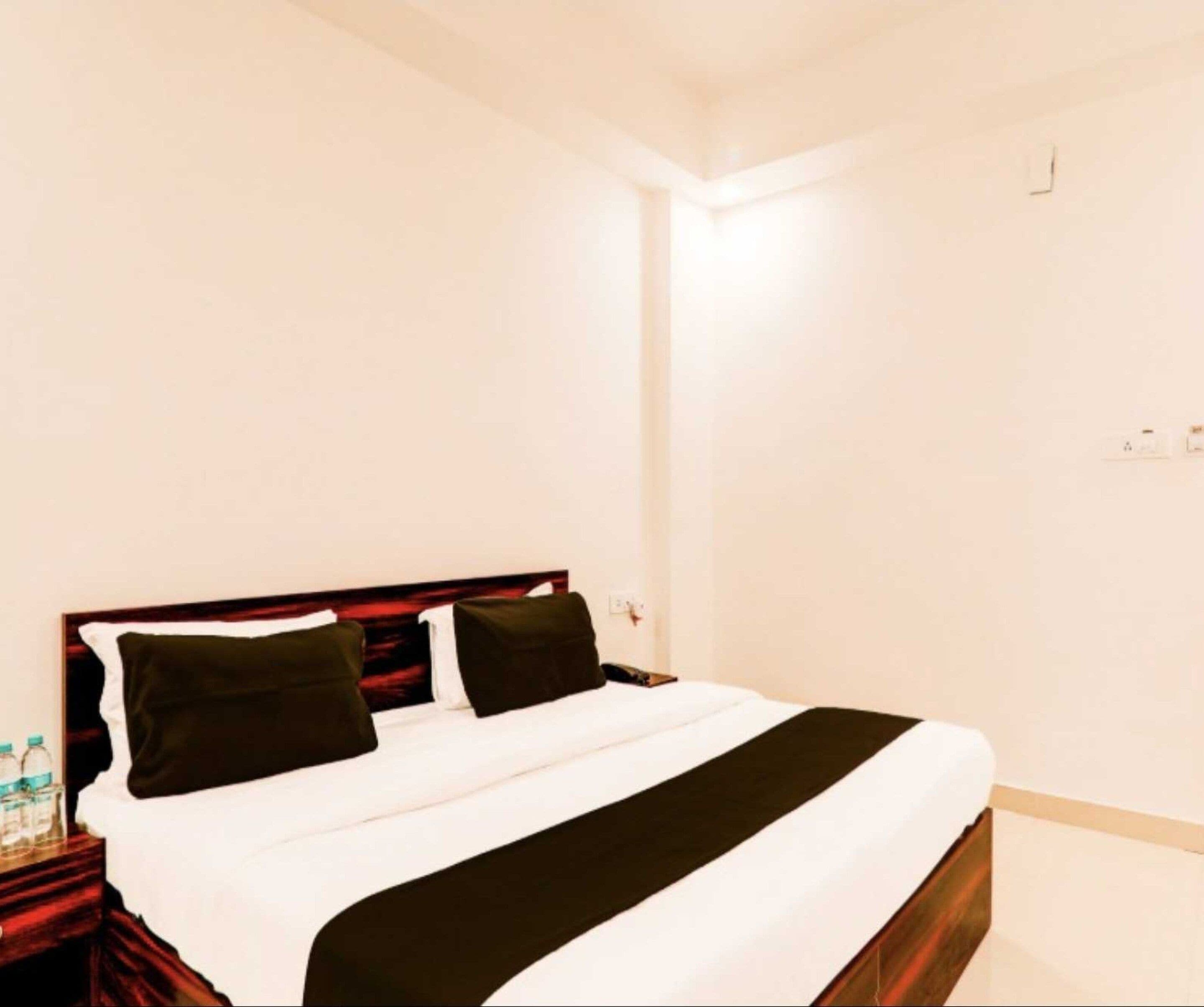 A hotel room with a bed, a nightstand, and a wall socket.