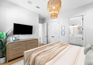 Une chambre à coucher avec un lit, une télévision, une commode et un miroir.