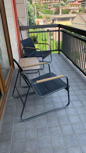 A balcony with two black lounge chairs and a wooden table. - Spazioso appartamento vicino a laghi e aeroporto con parcheggio privato gratuito (Trescore Balneario)