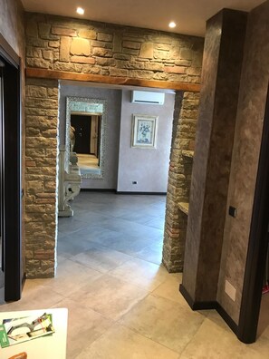 A hallway with stone walls, a staircase, and a framed picture on the wall. - Spazioso appartamento vicino a laghi e aeroporto con parcheggio privato gratuito (Trescore Balneario)