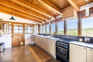 A modern kitchen with wooden beams, large windows, and a view of the outdoors. - Ecofinca Lo Mas (Tortosa)