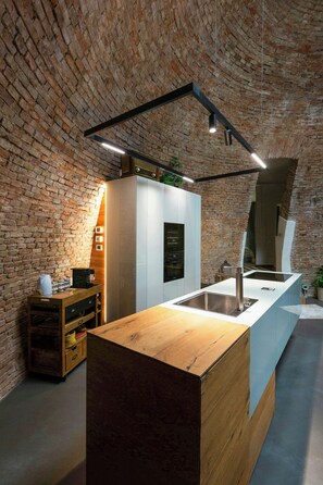 Une cuisine avec un mur en briques, un comptoir en bois et des appareils électroménagers modernes.