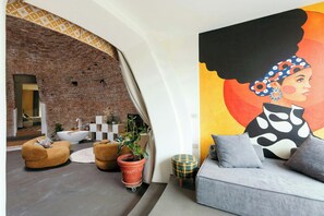 A modern living room with a brick wall, a large painting, and a grey sofa with cushions. - Renovated Icehouse Along Wine and Food Trails (Anzola dell'emilia)